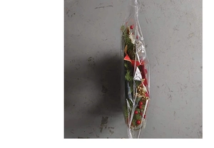 Detail view of a festive Christmas wreath with red berries and golden ornaments in packaging