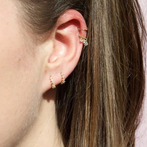 Detailed view of gold S925 sterling silver starburst ear cuffs and heart drop earrings
