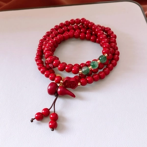Detailed view of red cinnabar beads with green spacers and a gourd pendant bracelet