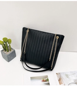 Detail of black woven texture tote bag featuring a gold chain strap and PU leather finish