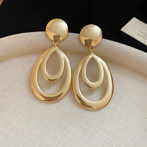 Détail de boucles d'oreilles goutte dorées évidées avec finition polie miroir moderne