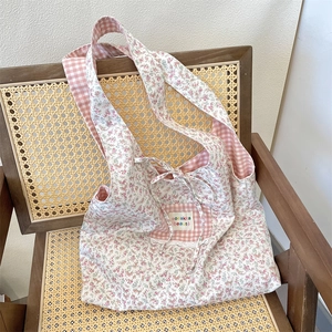 Detailed patchwork floral and pink check canvas tote with decorative bow on a wooden chair