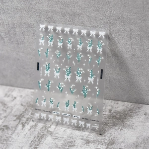 Close-up of lily of the valley nail stickers with white bows and green leaf patterns