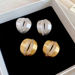Detailed macro view of brushed metal C-shape stud earrings with micro-set zircon stones