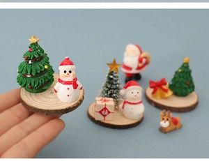 Close-up of miniature Christmas tree and snowman figure on a natural wooden base