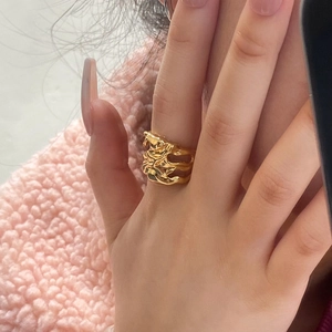 Vue détaillée d'une bague dorée ajustable avec design texturé de lave sur la main du mannequin
