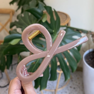 Macro detail of nude pink hair claw clip showing infinity design and golden spring