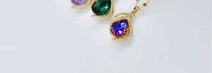 Macro shot of three teardrop crystal pendants in purple, green and blue-violet hues