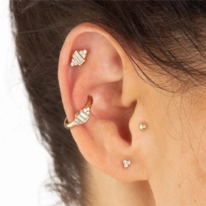 Macro shot of gold floral stacking earring set with zircon stones on a model's ear