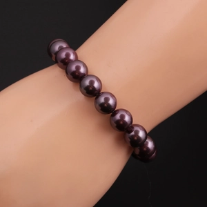 Detailed view of 10mm purple shell pearl bracelet worn on model with black background