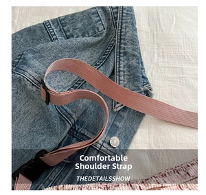Detail of blue denim bag featuring pink woven strap and durable plastic buckle closure