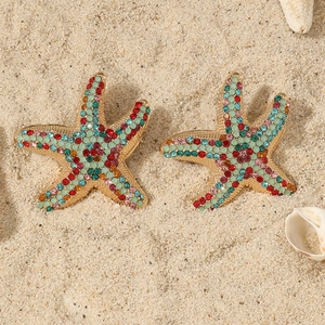 Detailed macro view of colorful starfish earrings with vibrant rhinestones on sand
