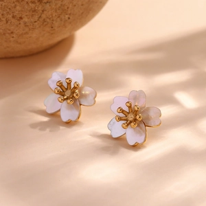 Macro detail of cherry blossom stud earrings with white petals and golden stamens