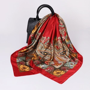 Detail of red paisley silk scarf draped over a black crocodile pattern luxury handbag