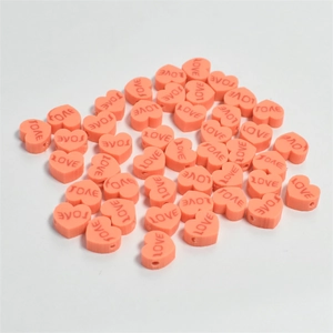 Macro shot of 10mm coral heart-shaped resin beads with LOVE engraving for DIY crafts
