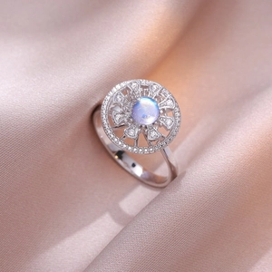 Silberring mit blauem Mondstein und weißen Zirkonia auf Seidenhintergrund, Blumendesign