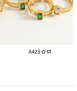 Detail of twisted gold ring band featuring emerald and clear baguette gemstones