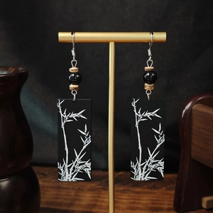 Detail of vintage bamboo leaf earrings hanging on a gold display stand with elegant tassels
