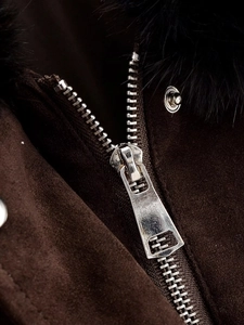 Detail of silver metal zipper and soft black fur collar on a brown parka jacket