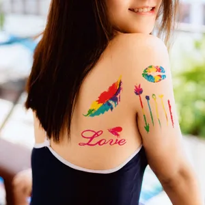 Detail of colorful waterproof temporary tattoos featuring feathers and rainbow lip prints
