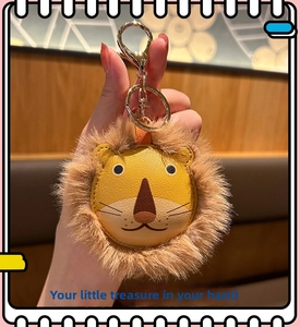 Detail of plush lion keychain with yellow faux leather face and golden metal clasp