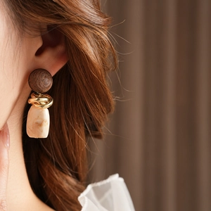 Close-up of vintage geometric earring with wood beads and resin pendant on model