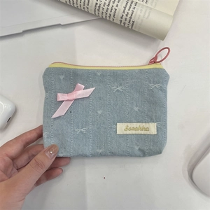 Dettaglio del portamonete in denim azzurro con fiocco di raso rosa e cerniera
