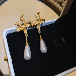Detail of gold floral earrings with teardrop pearls on black velvet jewelry display