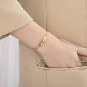 Close-up of gold infinity charm herringbone bracelet with white zircon micro-inlays