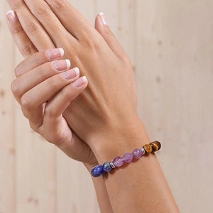 Detail of 8mm amethyst and tiger eye stone yoga bracelet on wrist with wooden background