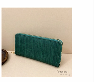 Macro detail of dark green vintage textured long purse with golden metal zipper closure