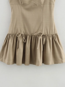 Detail of khaki dress with pleated hem, symmetrical bow ties, and fine twill texture