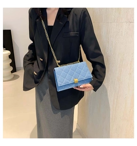 Detail of blue denim crossbody bag with quilted pattern and golden chain strap