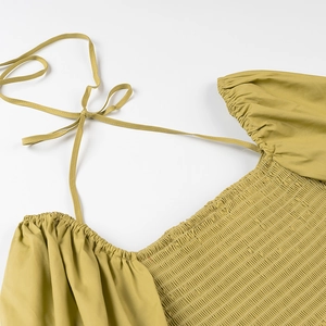 Detail view of olive green blouse with square neck, puff sleeves and ruched waist details