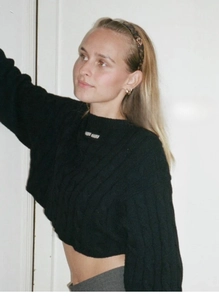 Close-up of black cable knit sweater styled with chic tortoiseshell heart headband