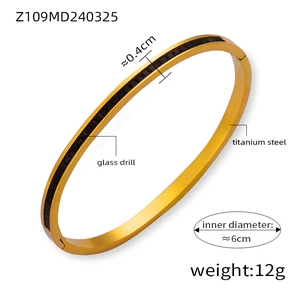 Detail of gold titanium steel bangle featuring an inlay of black glass drill accents