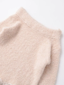 Close-up of beige fuzzy knit texture with delicate white lace trim on the bottom edge
