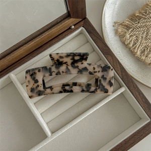 Detail shot of large acetate leopard print hair claw clip in a wooden jewelry box