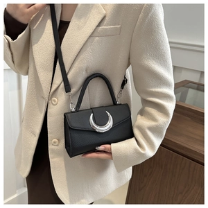 Détail du sac bandoulière noir grainé avec une boucle métallique argentée en demi-lune