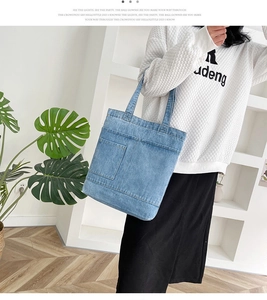 Dettaglio della borsa tote in denim azzurro lavato con una pratica tasca frontale per l'uso