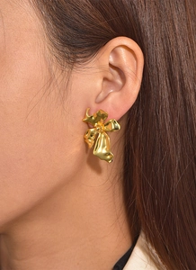 Close-up of gold flower stud earring with irregular texture worn by a model