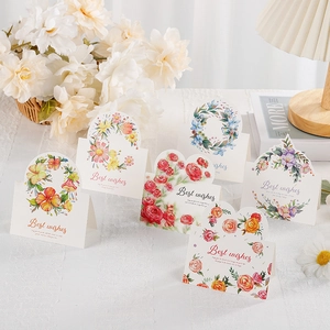 Five assorted 3D floral greeting cards with Best Wishes text on a cozy home desk setup