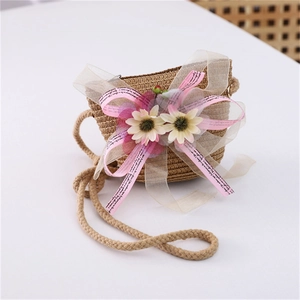 Detail of summer straw crossbody bag with pink floral ribbon and natural woven texture