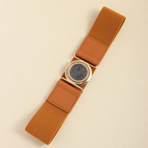 Detail of a brown elastic waist belt featuring a gold round buckle with rhinestones