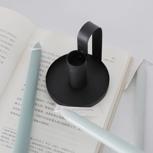 Minimalist black matte iron candle holder with scented candle on an open book