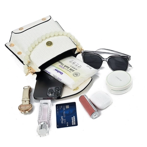 White textured mini shoulder bag with pearl handle and accessories showing storage capacity