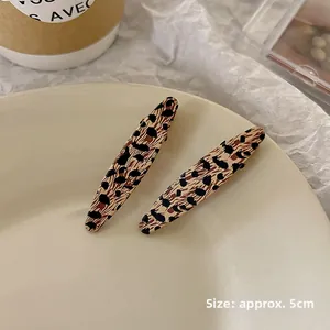 Close-up of leopard print bow hair clips in a ceramic tray showing the 5cm size detail