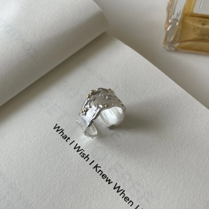 Irregular textured S925 sterling silver ring with gold accents on an open book