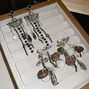 Macro shot of silver needle crystal flower drop tassel earrings on a velvet display tray