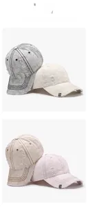 Detail view of washed cotton baseball caps with distressed holes and metal logo accents